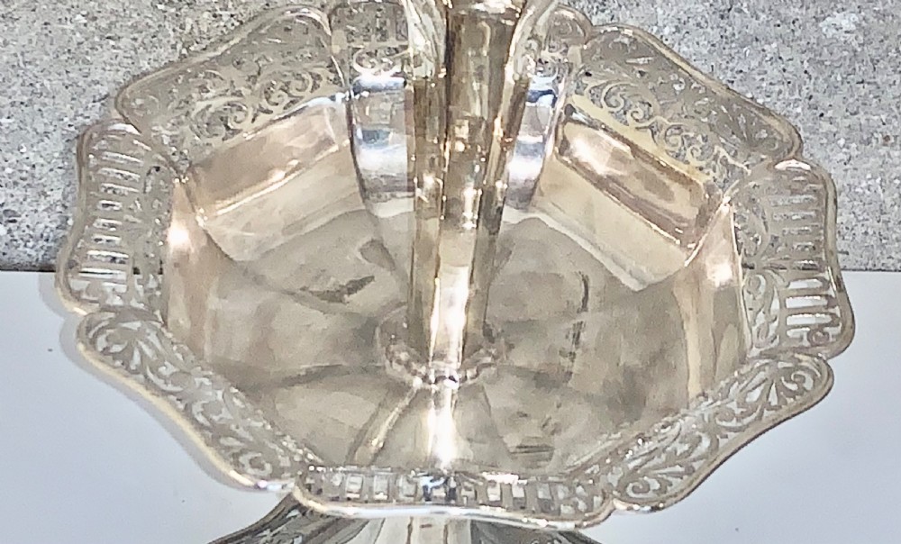 An Edwardian sterling silver two-tiered centrepiece with pierced decorative borders, a flared pedestal column, and a shaped hexagonal base. View IV