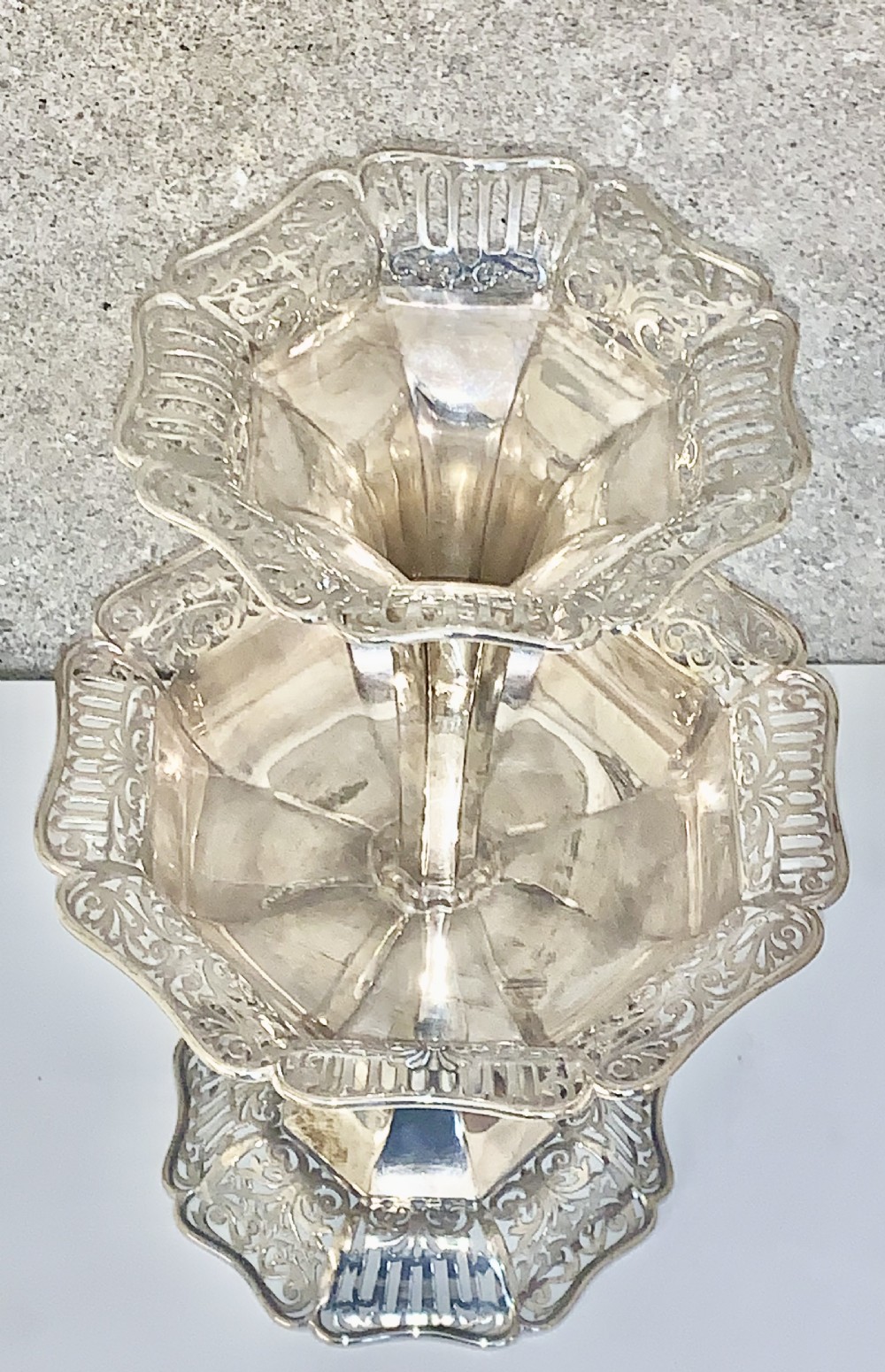 An Edwardian sterling silver two-tiered centrepiece with pierced decorative borders, a flared pedestal column, and a shaped hexagonal base. View VI