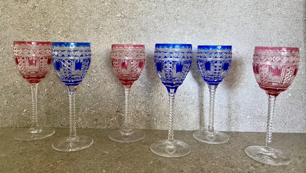 A set of six cut-to-clear crystal wine glasses with alternating cobalt blue and ruby red bowls on tall faceted stems. View VI