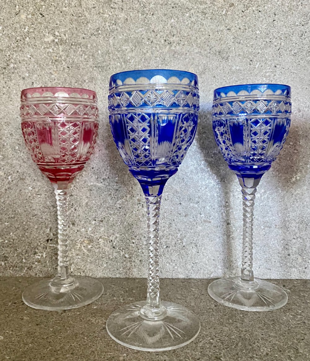 A set of six cut-to-clear crystal wine glasses with alternating cobalt blue and ruby red bowls on tall faceted stems. View IX