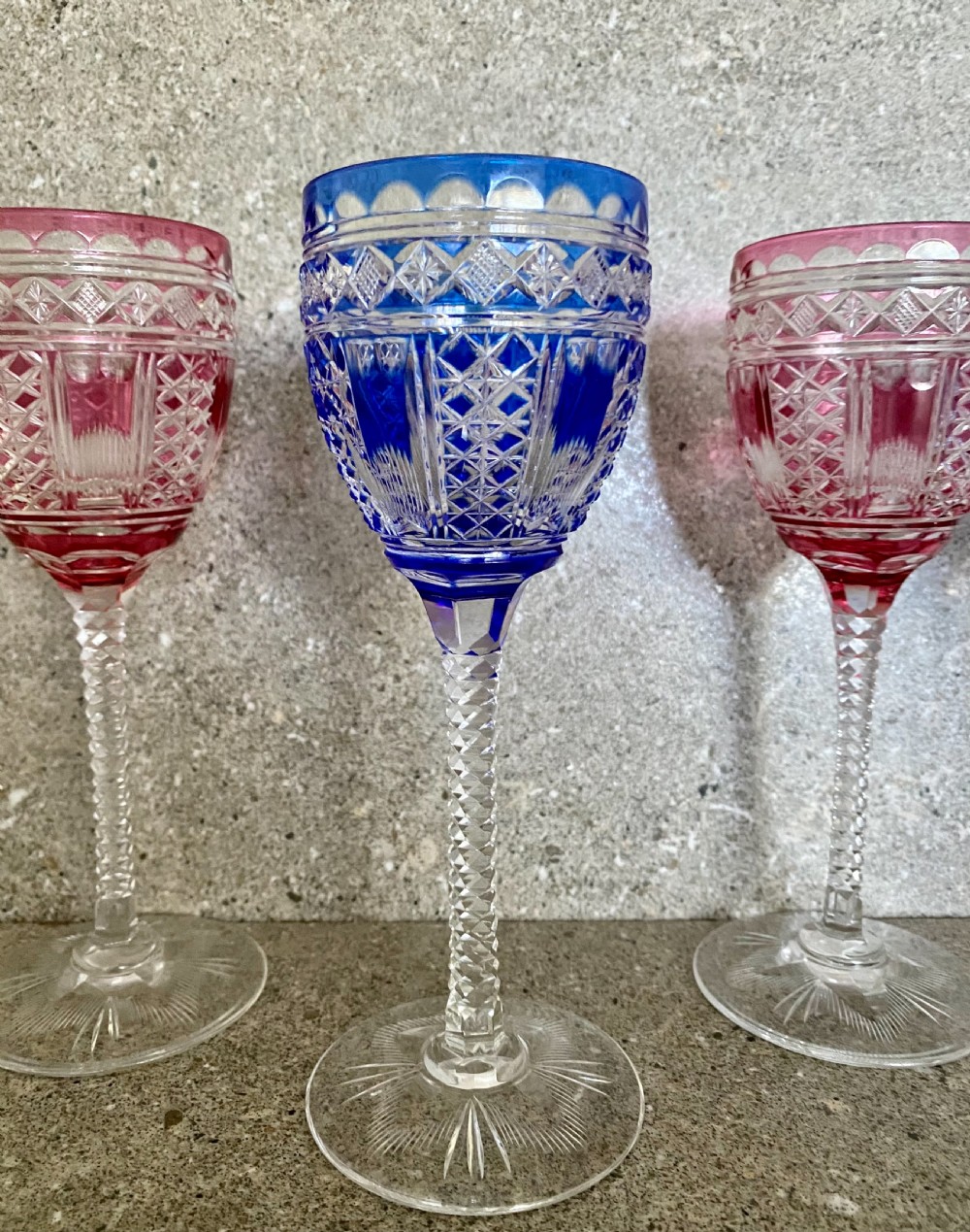 A set of six cut-to-clear crystal wine glasses with alternating cobalt blue and ruby red bowls on tall faceted stems. View XII