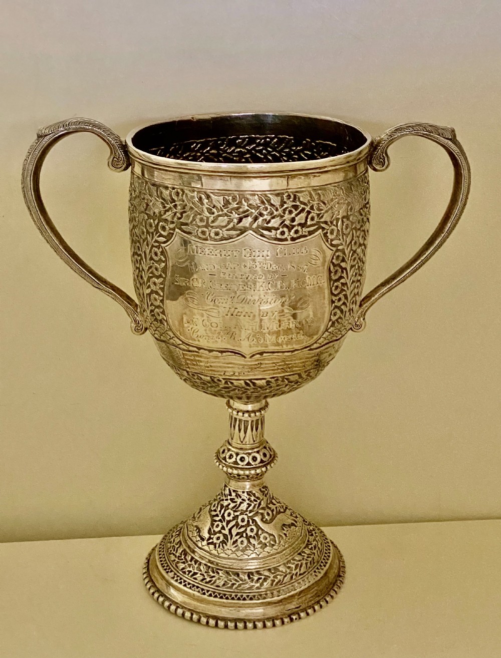 A 19th-century Indian Kutch silver trophy cup featuring dense chased floral motifs, twin scrolled handles, and an engraved central cartouche. View II