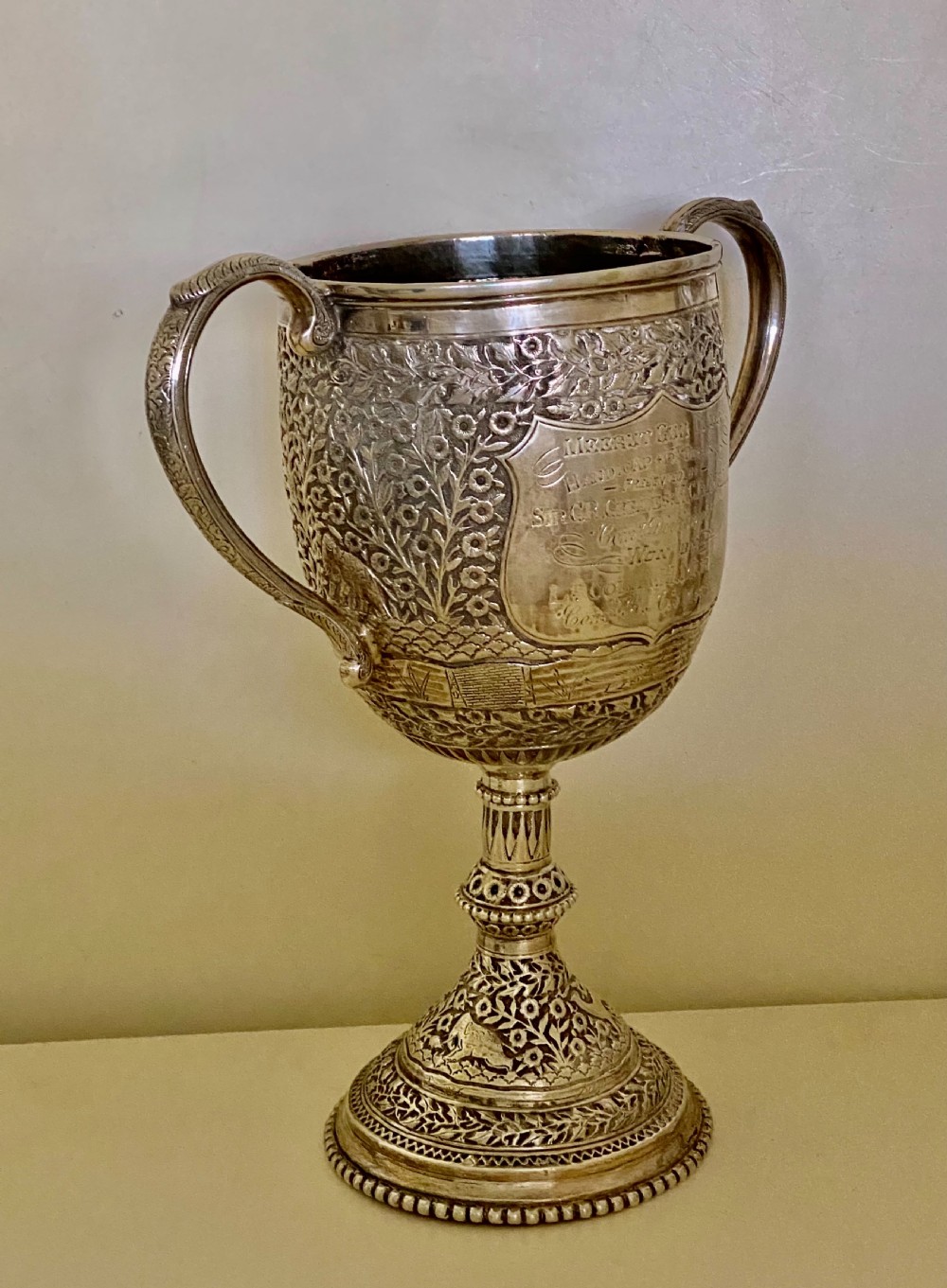 A 19th-century Indian Kutch silver trophy cup featuring dense chased floral motifs, twin scrolled handles, and an engraved central cartouche. View III