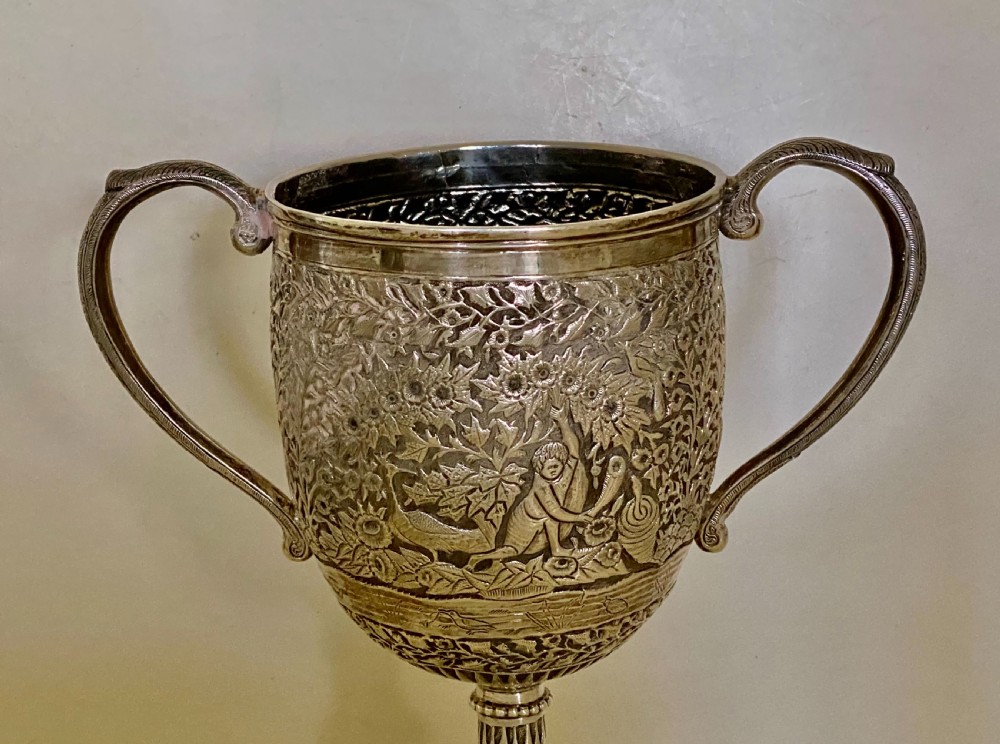 A 19th-century Indian Kutch silver trophy cup featuring dense chased floral motifs, twin scrolled handles, and an engraved central cartouche. View VII