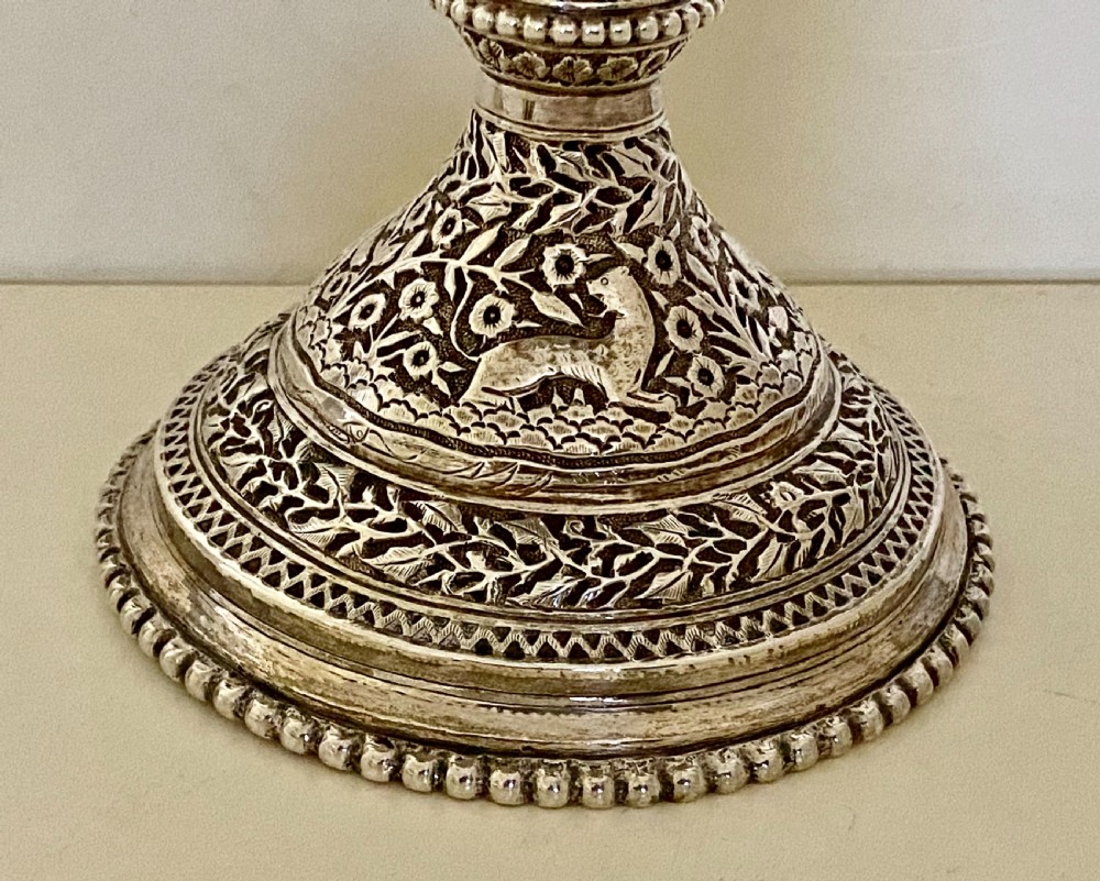 A 19th-century Indian Kutch silver trophy cup featuring dense chased floral motifs, twin scrolled handles, and an engraved central cartouche. View X