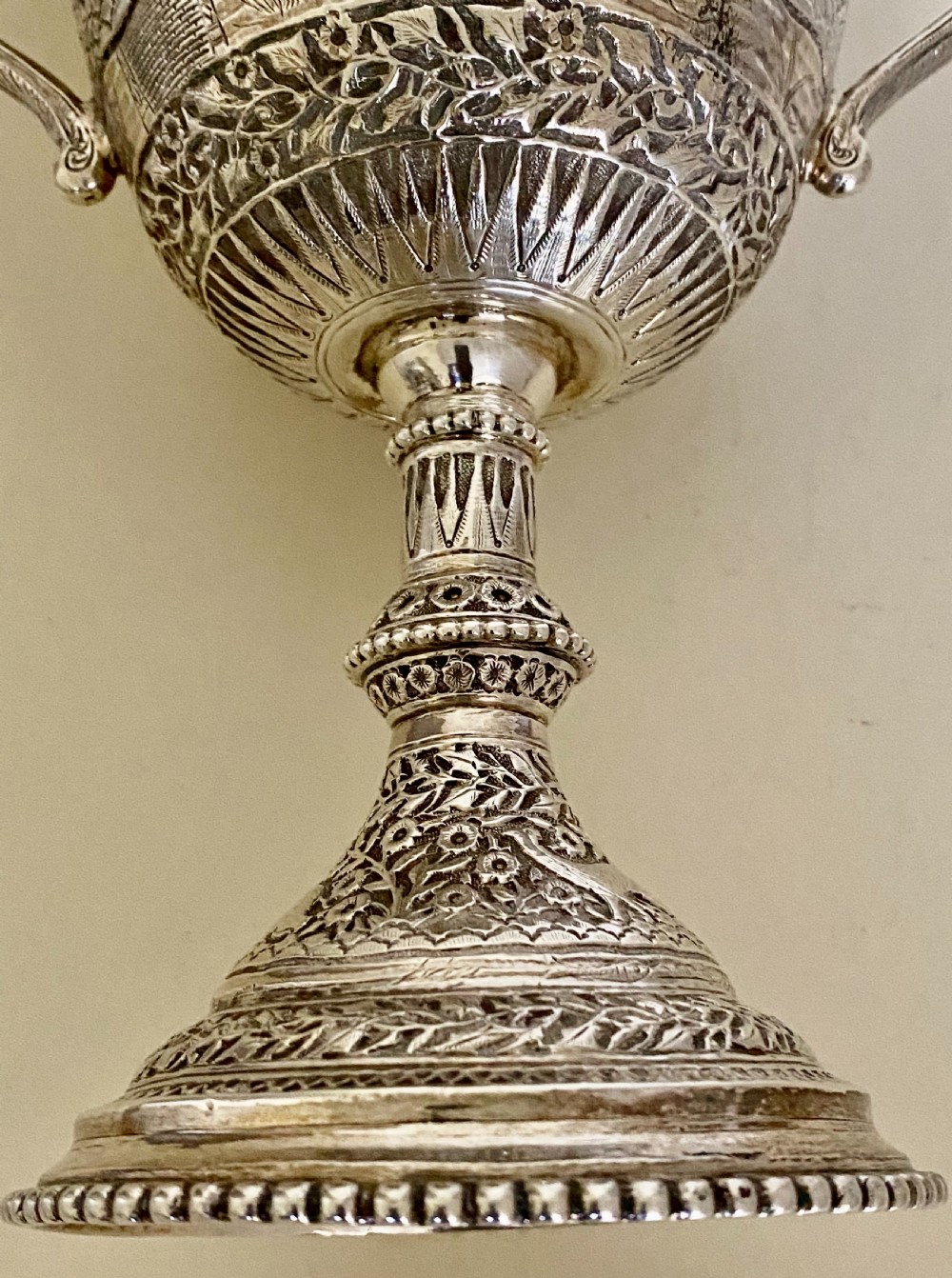 A 19th-century Indian Kutch silver trophy cup featuring dense chased floral motifs, twin scrolled handles, and an engraved central cartouche. View XII