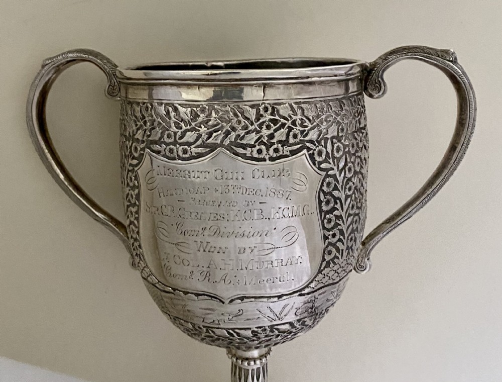 A 19th-century Indian Kutch silver trophy cup featuring dense chased floral motifs, twin scrolled handles, and an engraved central cartouche. View XV