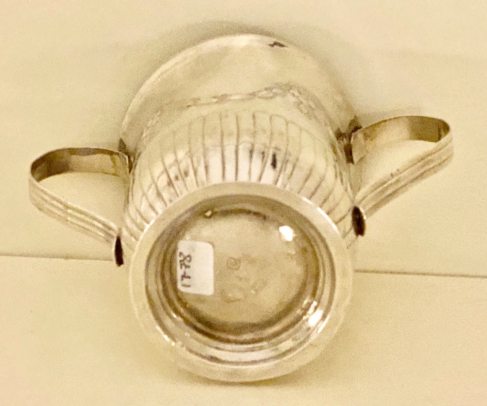 A George III sterling silver two-handled porringer featuring embossed floral swags and vertical fluting around the base. View IV