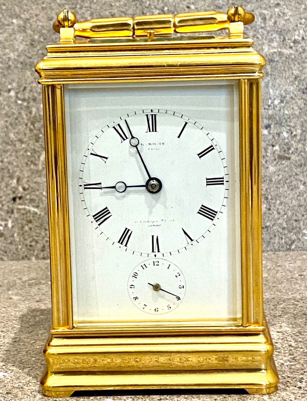 A nineteenth-century gilt brass repeating carriage clock featuring a white enamel dial with Roman numerals, a subsidiary alarm dial, glass side panels, and a hinged top handle. View XI