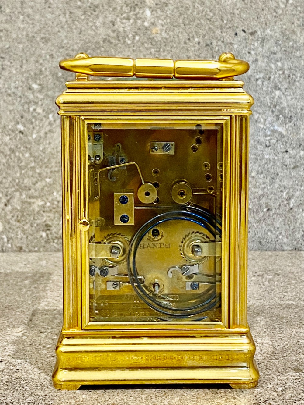 A nineteenth-century gilt brass repeating carriage clock featuring a white enamel dial with Roman numerals, a subsidiary alarm dial, glass side panels, and a hinged top handle. View VI