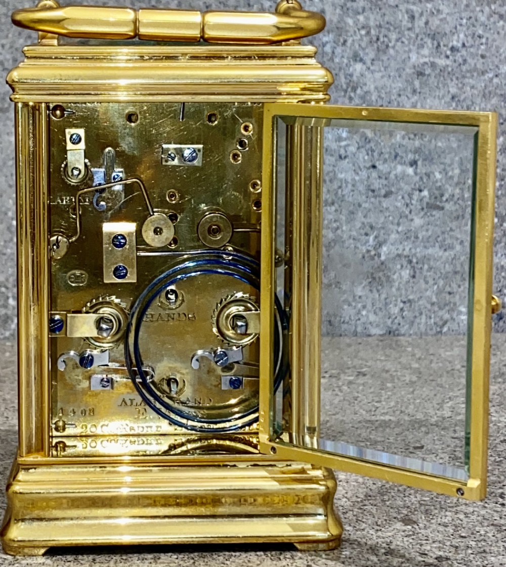 A nineteenth-century gilt brass repeating carriage clock featuring a white enamel dial with Roman numerals, a subsidiary alarm dial, glass side panels, and a hinged top handle. View VII