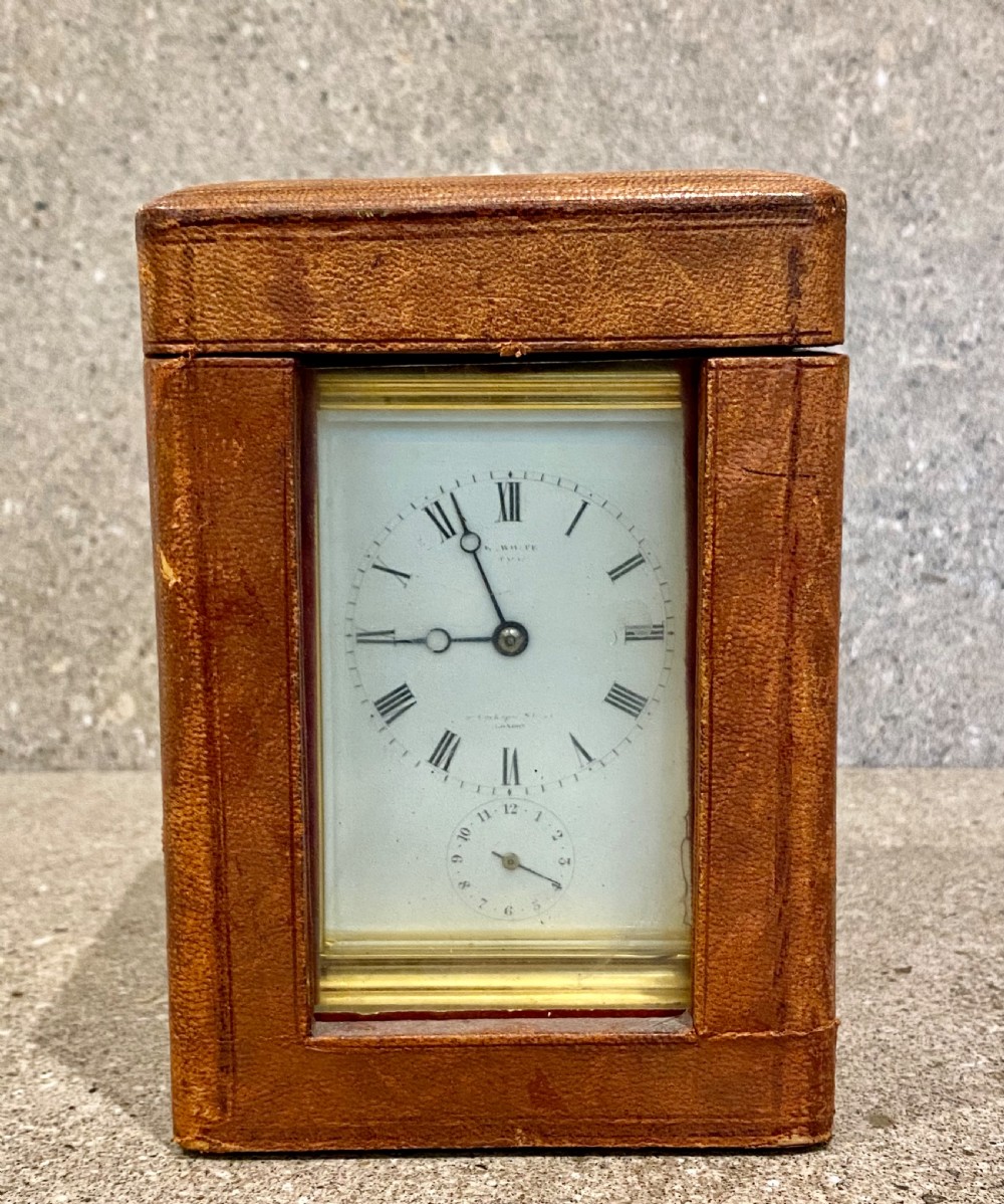 A nineteenth-century gilt brass repeating carriage clock featuring a white enamel dial with Roman numerals, a subsidiary alarm dial, glass side panels, and a hinged top handle. View VIII