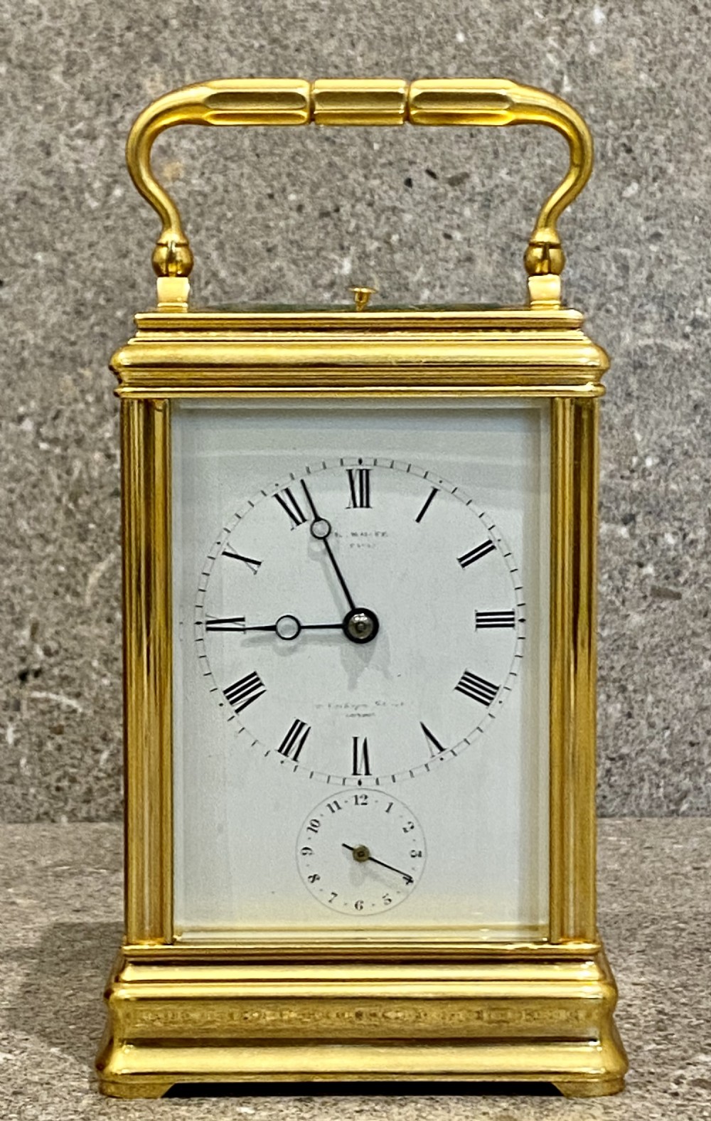 A nineteenth-century gilt brass repeating carriage clock featuring a white enamel dial with Roman numerals, a subsidiary alarm dial, glass side panels, and a hinged top handle. View X