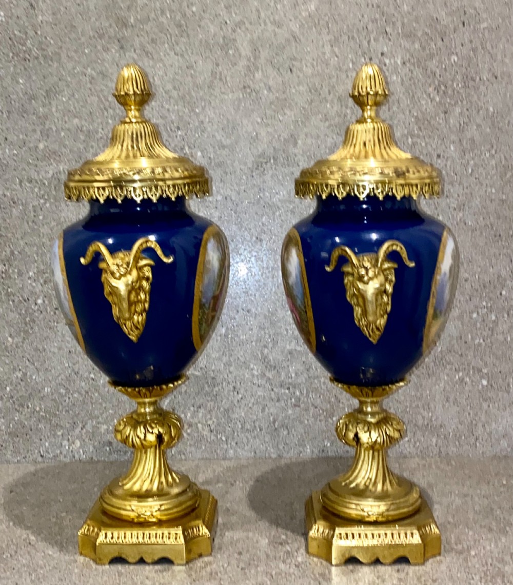 A three-piece French clock garniture set featuring a central gilt bronze mounted cobalt blue porcelain clock flanked by two matching urns with hand-painted figurative reserves. View IV