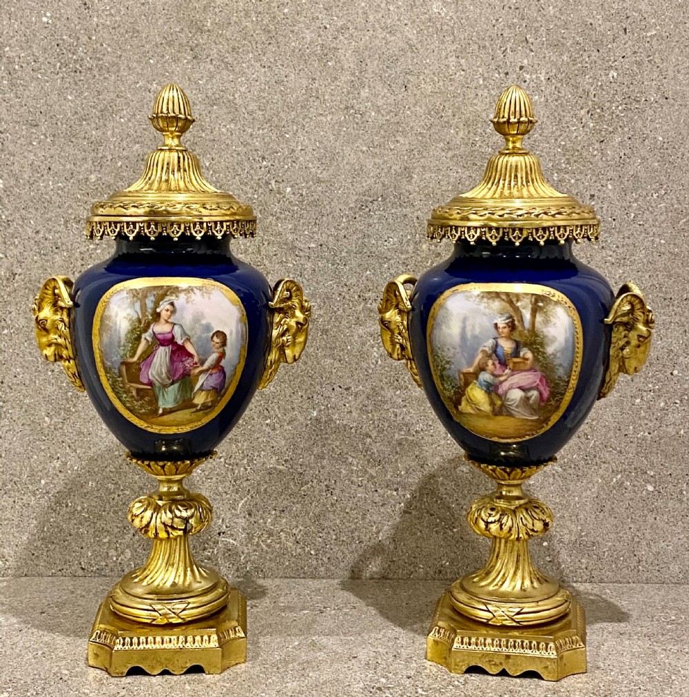 A three-piece French clock garniture set featuring a central gilt bronze mounted cobalt blue porcelain clock flanked by two matching urns with hand-painted figurative reserves. View X