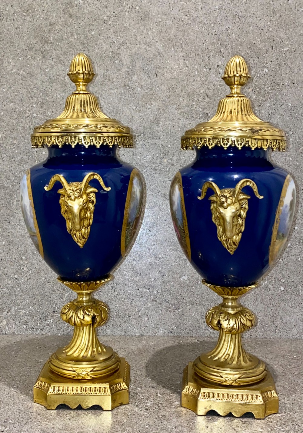 A three-piece French clock garniture set featuring a central gilt bronze mounted cobalt blue porcelain clock flanked by two matching urns with hand-painted figurative reserves. View XIV