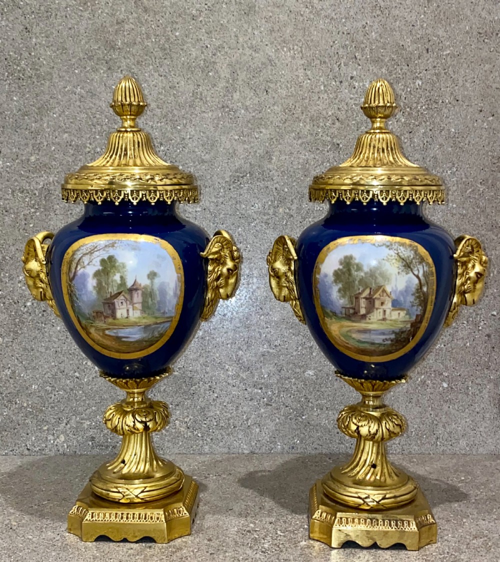 A three-piece French clock garniture set featuring a central gilt bronze mounted cobalt blue porcelain clock flanked by two matching urns with hand-painted figurative reserves. View XV