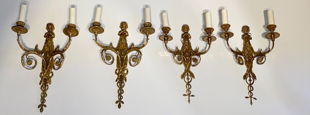 Set of four French gilt bronze two-branch wall sconces featuring central cherub figures and scrolling candle arms. View V