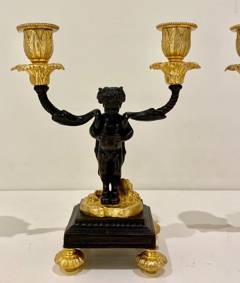 A pair of antique French gilt and patinated bronze two-light candelabra featuring dark bronze cherub figures holding gold candle arms on square bases. View III