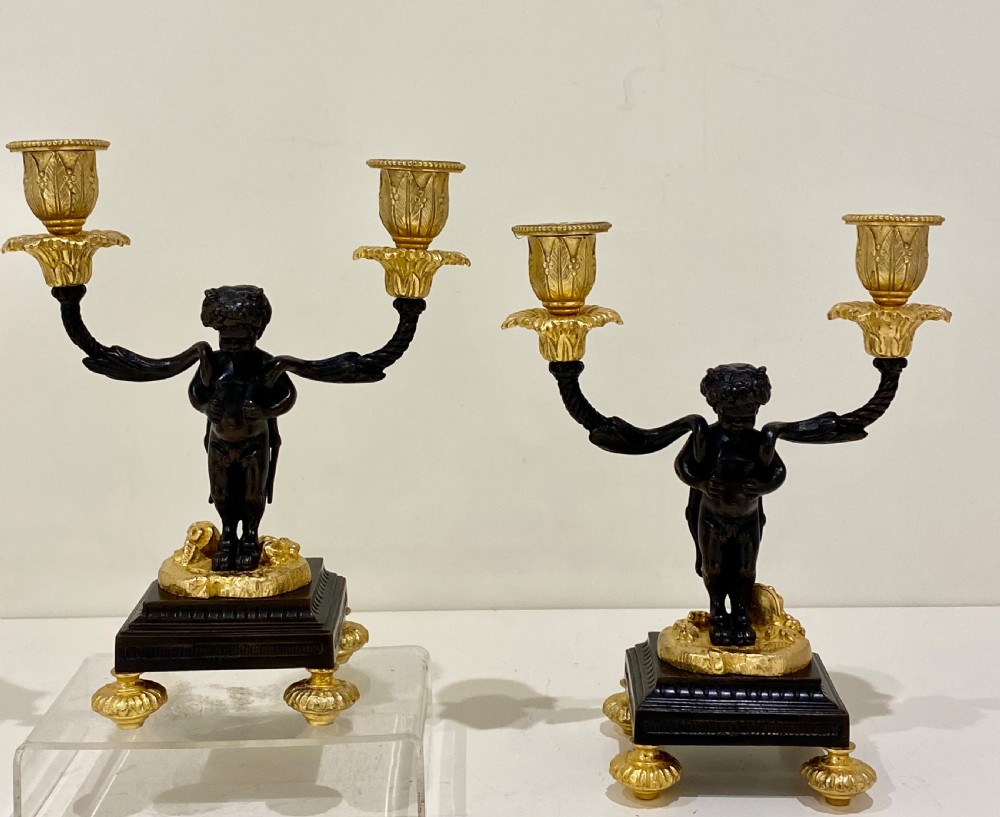 A pair of antique French gilt and patinated bronze two-light candelabra featuring dark bronze cherub figures holding gold candle arms on square bases. View VII