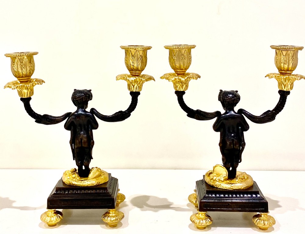 A pair of antique French gilt and patinated bronze two-light candelabra featuring dark bronze cherub figures holding gold candle arms on square bases. View XI