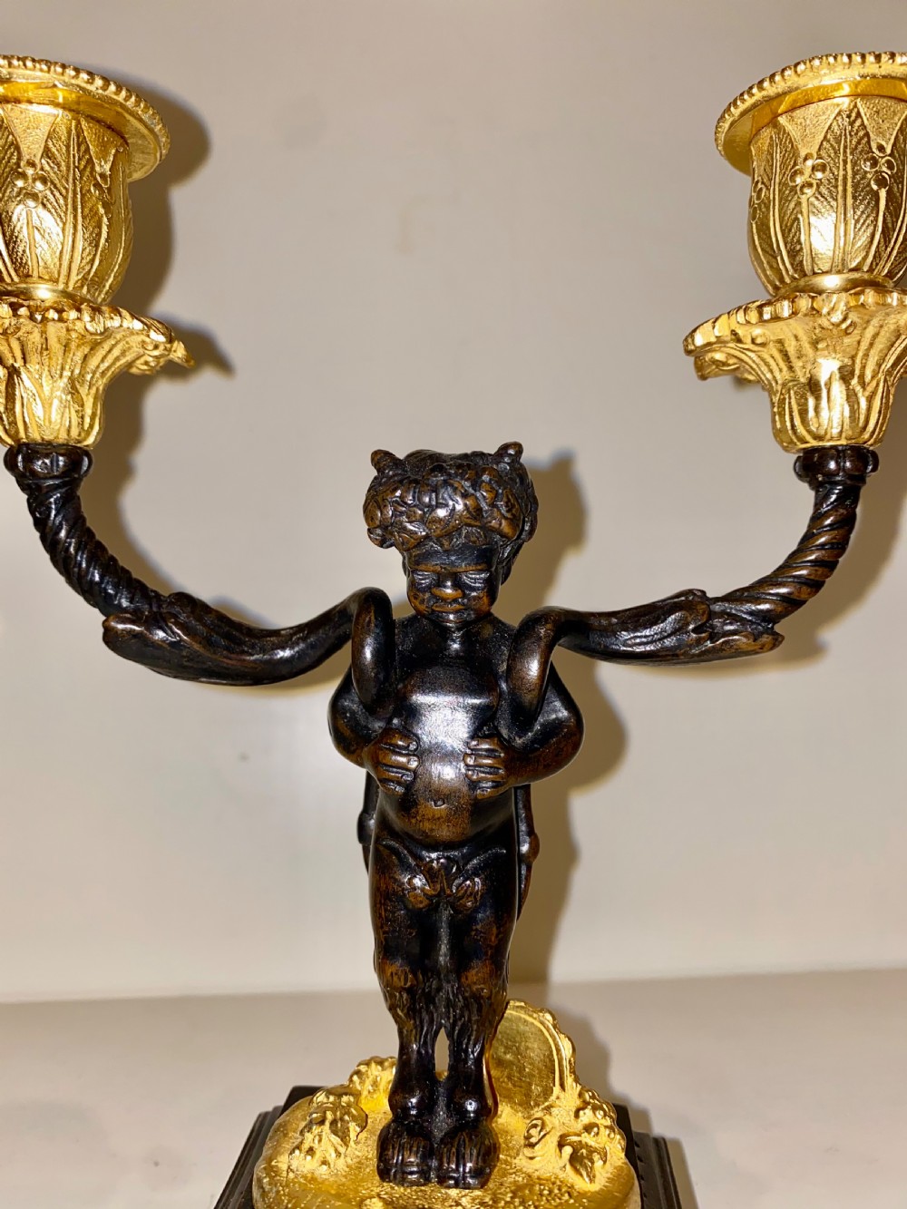 A pair of antique French gilt and patinated bronze two-light candelabra featuring dark bronze cherub figures holding gold candle arms on square bases. View XII