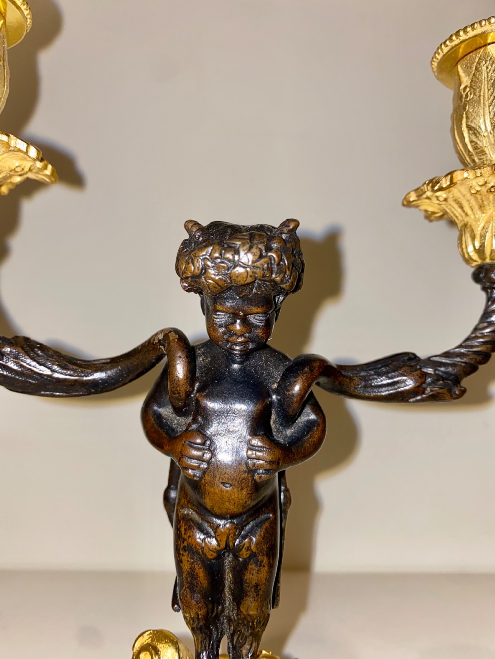 A pair of antique French gilt and patinated bronze two-light candelabra featuring dark bronze cherub figures holding gold candle arms on square bases. View XIII