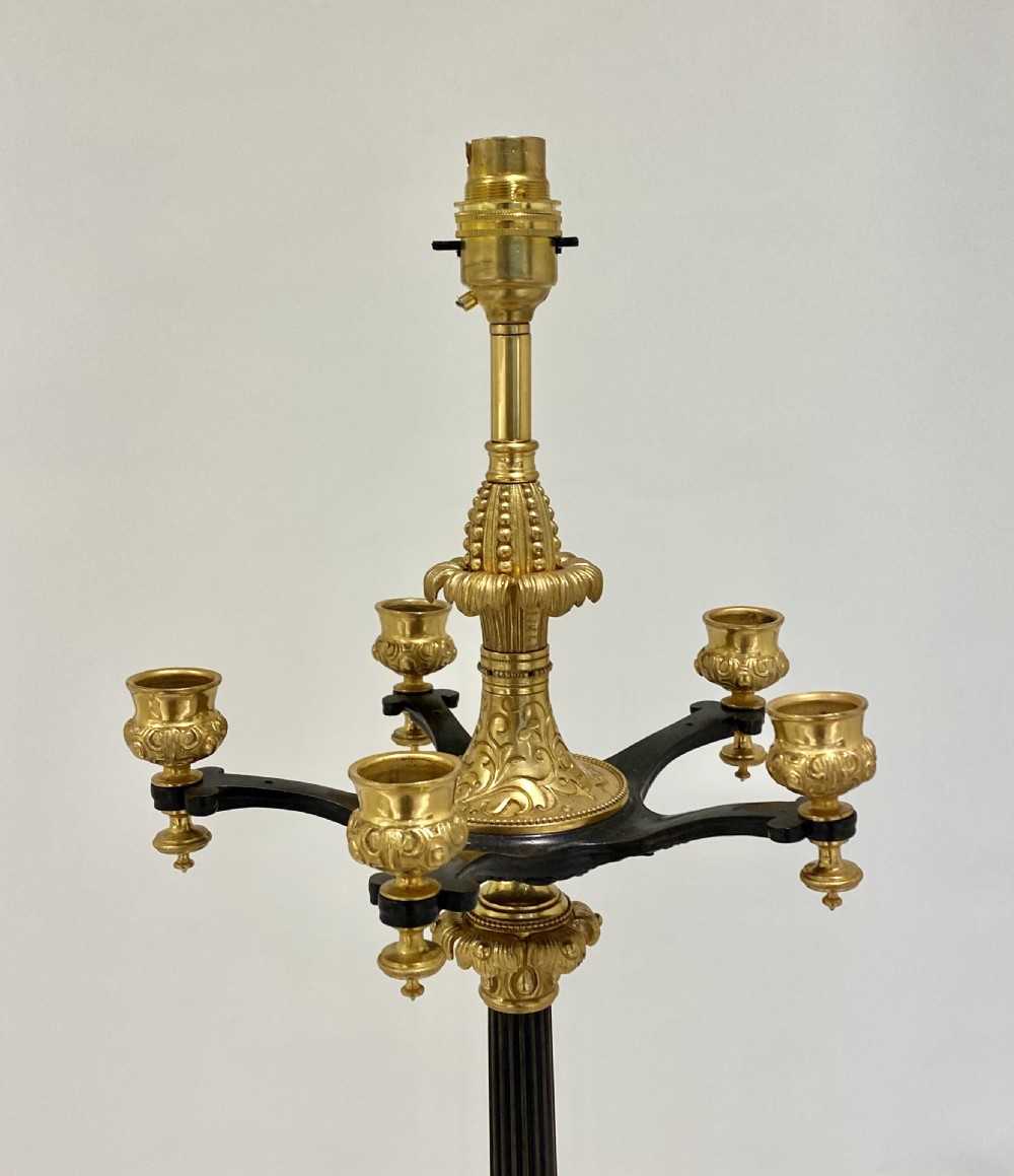 A 19th-century French Empire parcel-gilt and patinated bronze candelabra lamp with a fluted shaft, multiple candle arms, and a tripod paw base. View V