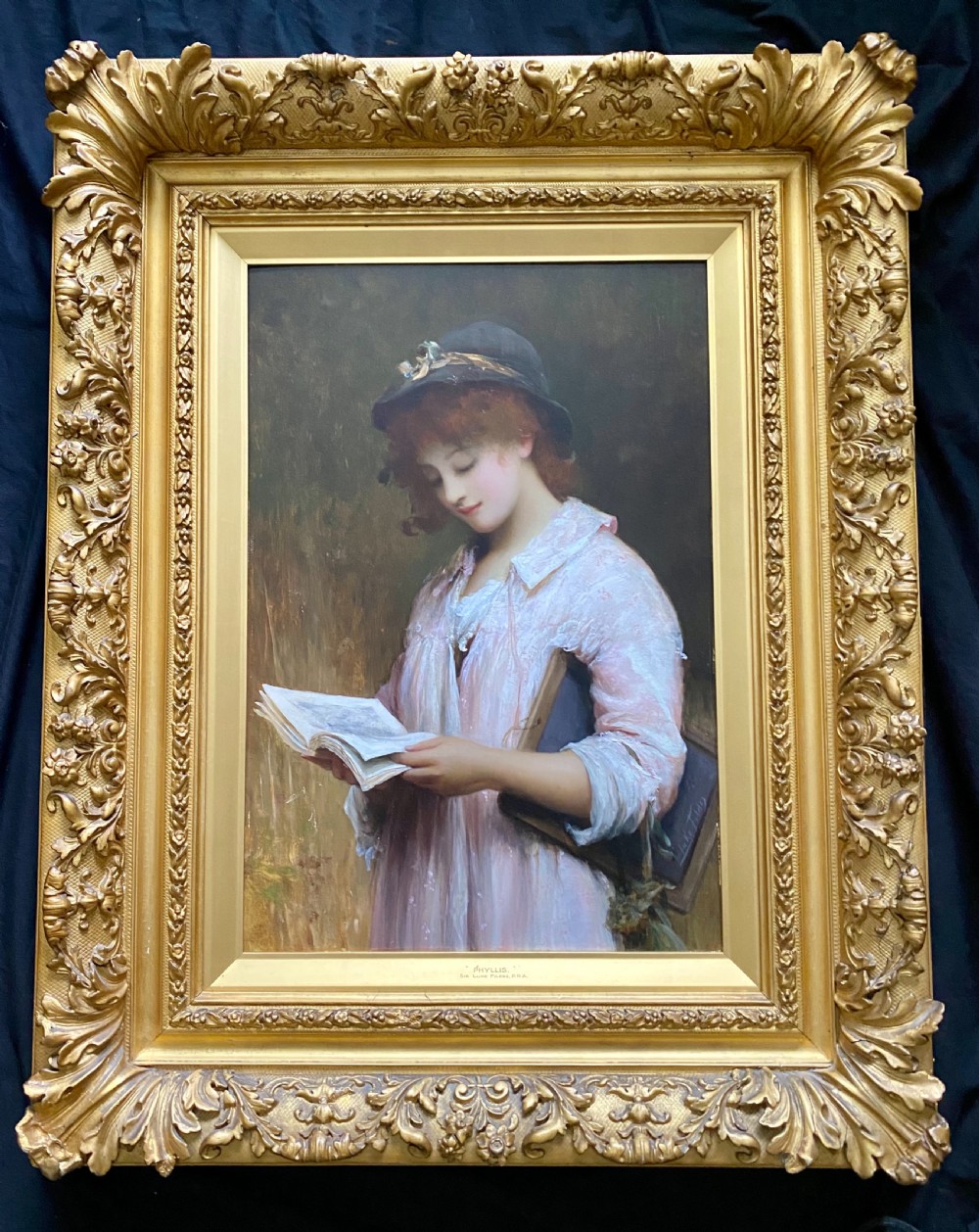 A Victorian oil portrait of a young woman in a pink garment holding an open book, set within an ornate gilded frame. View XVII