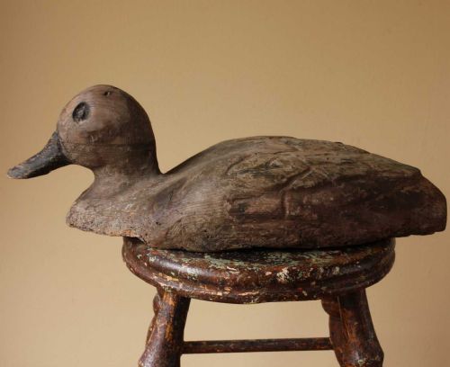 fig 1. A hand-carved rustic wooden decoy duck featuring a weathered grey finish and carved wing details.