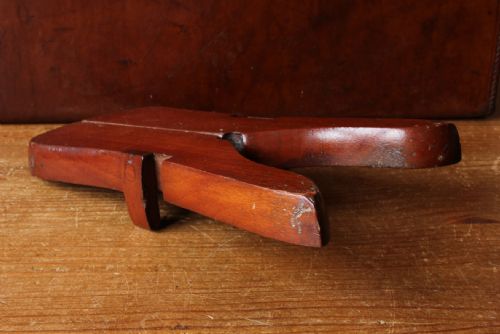 fig 1. A hinged reddish-brown wooden folding boot jack featuring brass fittings alongside two metal T-shaped boot pull hooks.
