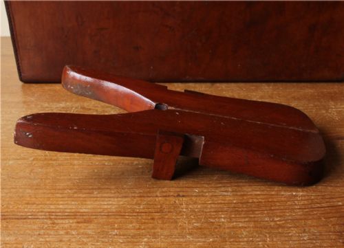 fig 2. A hinged reddish-brown wooden folding boot jack featuring brass fittings alongside two metal T-shaped boot pull hooks.