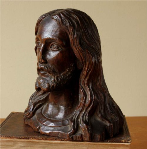 fig 1. A 19th-century hand-carved dark wood bust depicting Jesus Christ with long wavy hair, a beard, and detailed facial features.