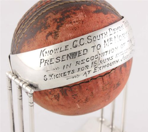 fig 1. A 1922 leather cricket ball mounted on a sterling silver stand formed as cricket wickets, featuring an engraved silver band across the centre.