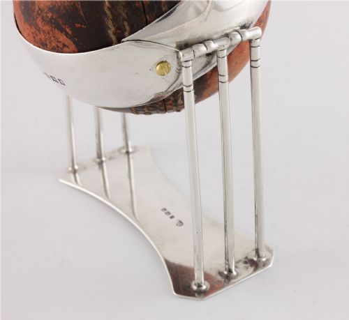 fig 2. A 1922 leather cricket ball mounted on a sterling silver stand formed as cricket wickets, featuring an engraved silver band across the centre.