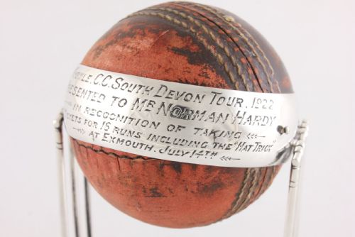 fig 3. A 1922 leather cricket ball mounted on a sterling silver stand formed as cricket wickets, featuring an engraved silver band across the centre.
