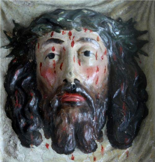 fig 1. A high-relief polychrome sculpture depicting the Veil of Veronica with the face of Jesus wearing a crown of thorns, presented inside a black glazed wooden shadowbox frame.