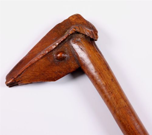 fig 1. A carved wooden Kanak bird head war club with a smooth tapered shaft and a beak-shaped terminal, crafted from dark brown hardwood.