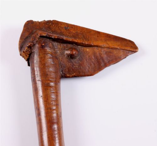 fig 2. A carved wooden Kanak bird head war club with a smooth tapered shaft and a beak-shaped terminal, crafted from dark brown hardwood.