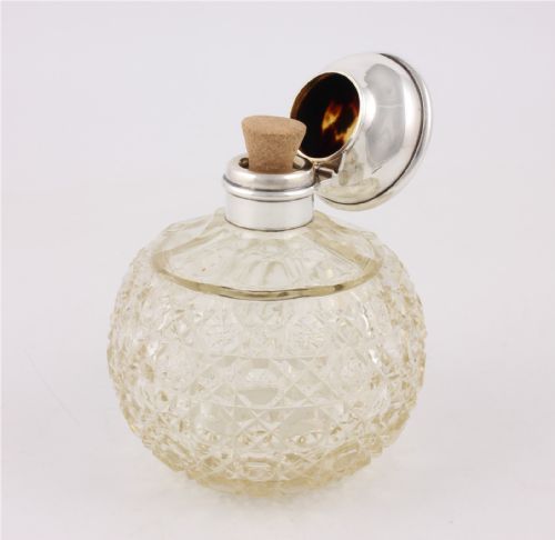 fig 1. A spherical cut glass scent bottle featuring a hallmarked sterling silver hinged cap inlaid with a round piece of tortoiseshell.
