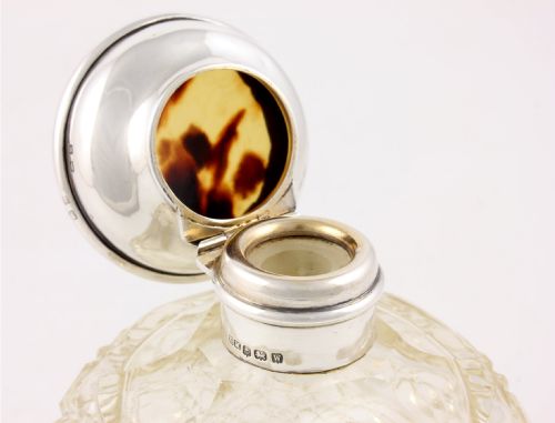 fig 2. A spherical cut glass scent bottle featuring a hallmarked sterling silver hinged cap inlaid with a round piece of tortoiseshell.
