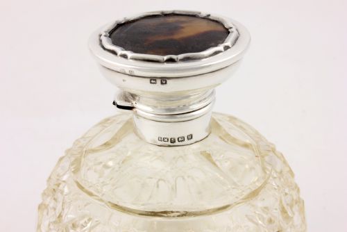 fig 3. A spherical cut glass scent bottle featuring a hallmarked sterling silver hinged cap inlaid with a round piece of tortoiseshell.