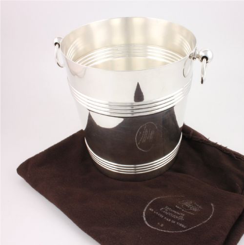 fig 1. A silver-plated cylindrical champagne cooler featuring horizontal ribbed banding and two side ring handles attached via spherical mounts.