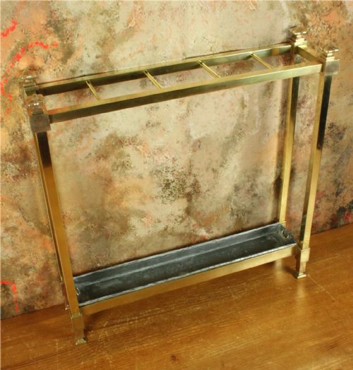 fig 1. A rectangular antique brass stick stand with four top compartments, corner finials, and a removable dark metal drip tray.