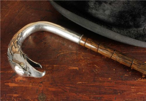 fig 1. An antique walking cane featuring an 800 silver handle sculpted in the shape of an eagle head, mounted on a dark ribbed wood shaft.