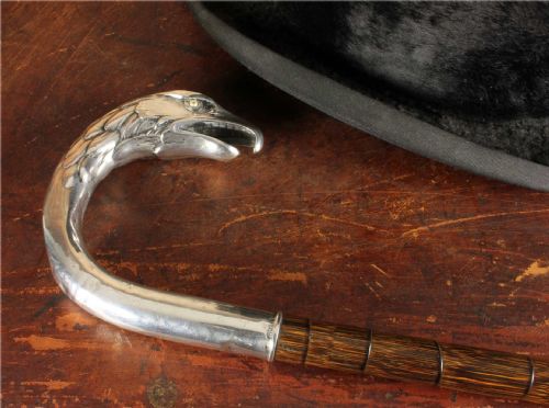 fig 2. An antique walking cane featuring an 800 silver handle sculpted in the shape of an eagle head, mounted on a dark ribbed wood shaft.