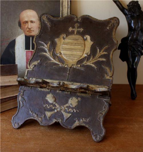 fig 1. An 18th-century carved wooden folding missal stand featuring a dark finish with gilded heraldic motifs and scalloped edges.