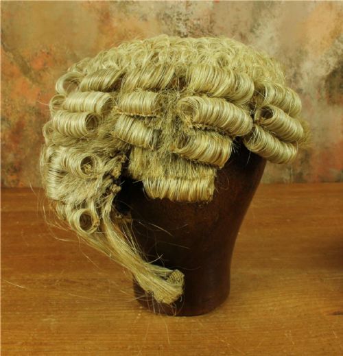 fig 2. A Victorian legal set containing a curled horsehair barrister wig, white cotton court bands, and an oval black metal tin decorated with gilded lettering.