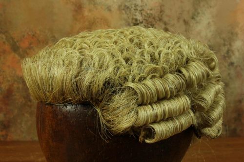 fig 3. A Victorian legal set containing a curled horsehair barrister wig, white cotton court bands, and an oval black metal tin decorated with gilded lettering.