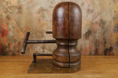 fig 1. An antique wooden hat stretcher featuring a split head block mounted on a timber base with a cast iron screw crank mechanism.